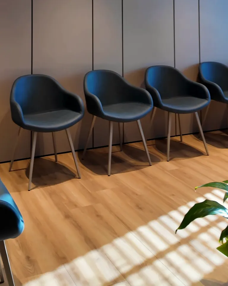 La sala d'attesa della clinica di Roncade: poltroncine blu petrolio, una pianta, il sole a strisce sul parquet