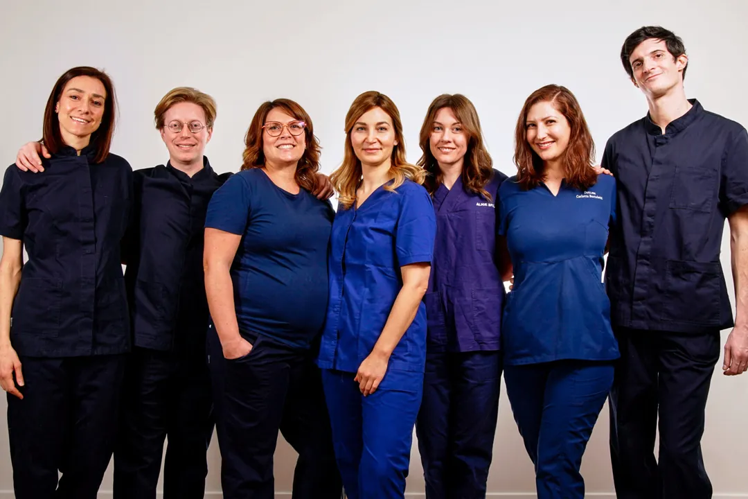 Sette medici della squadra abbracciati, in divisa, sorridenti